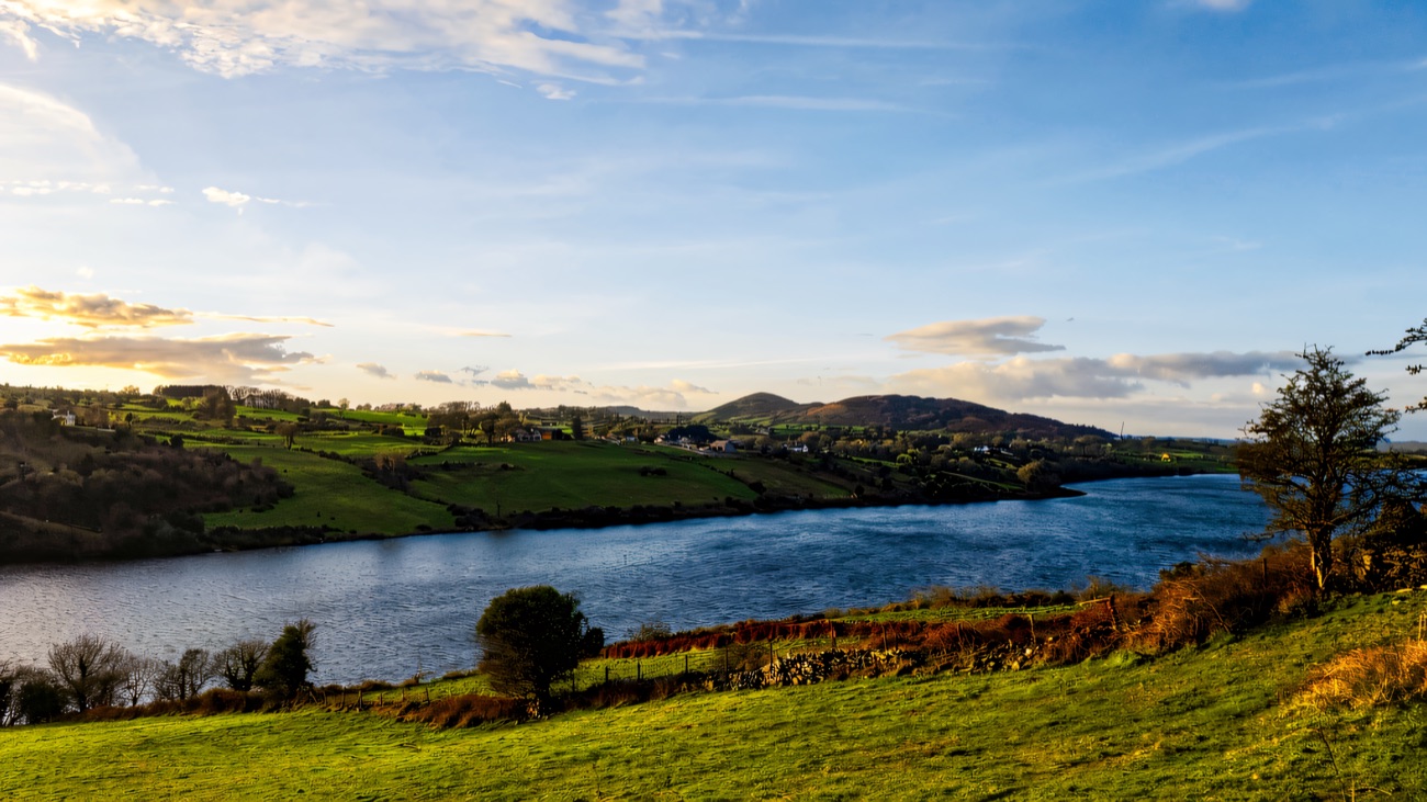 A bright blue-sky view across the lake to the rolling drumlins of south Armagh.