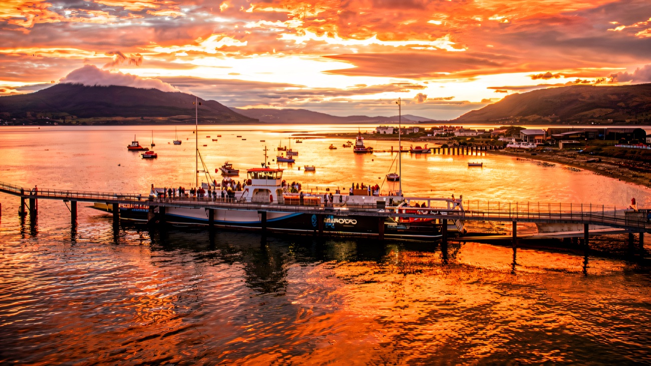 The ferry at its pier as a fiery sunset lights up the lough and hills.