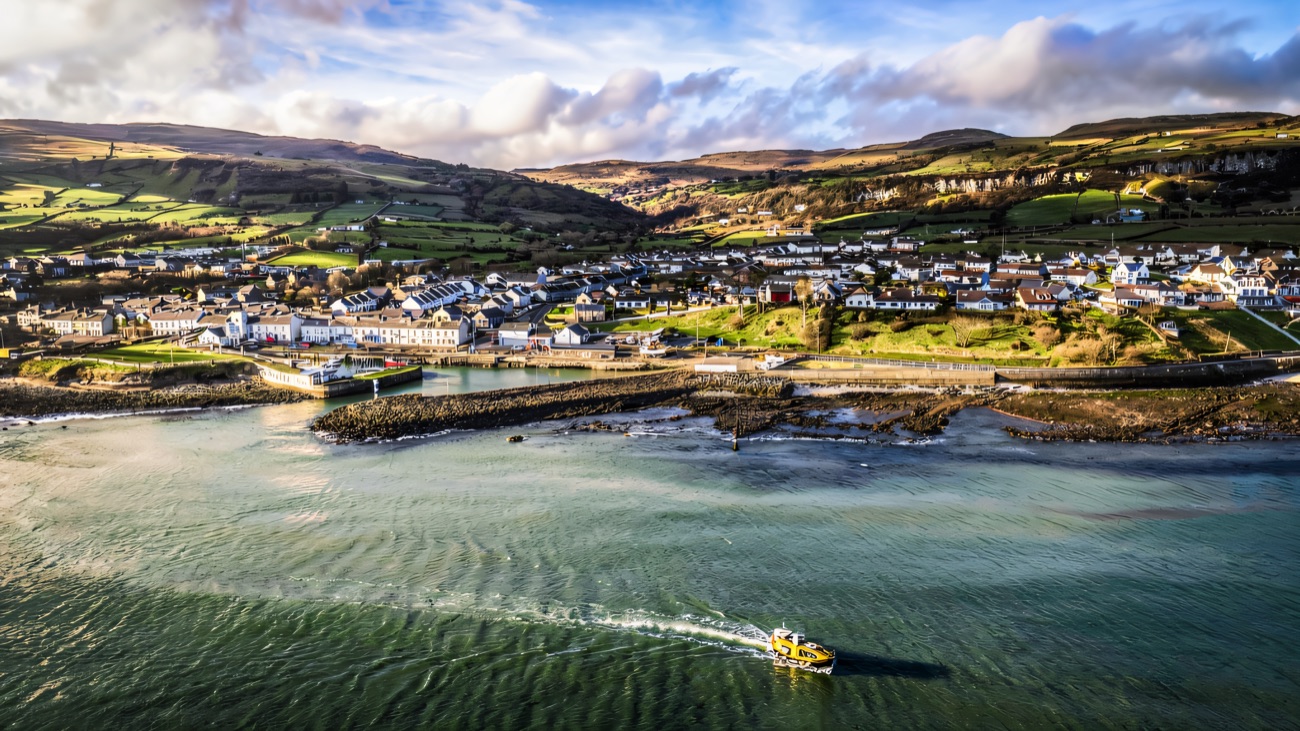 The yellow tour boat heading out from Carnlough into the bay, the Glens rising behind