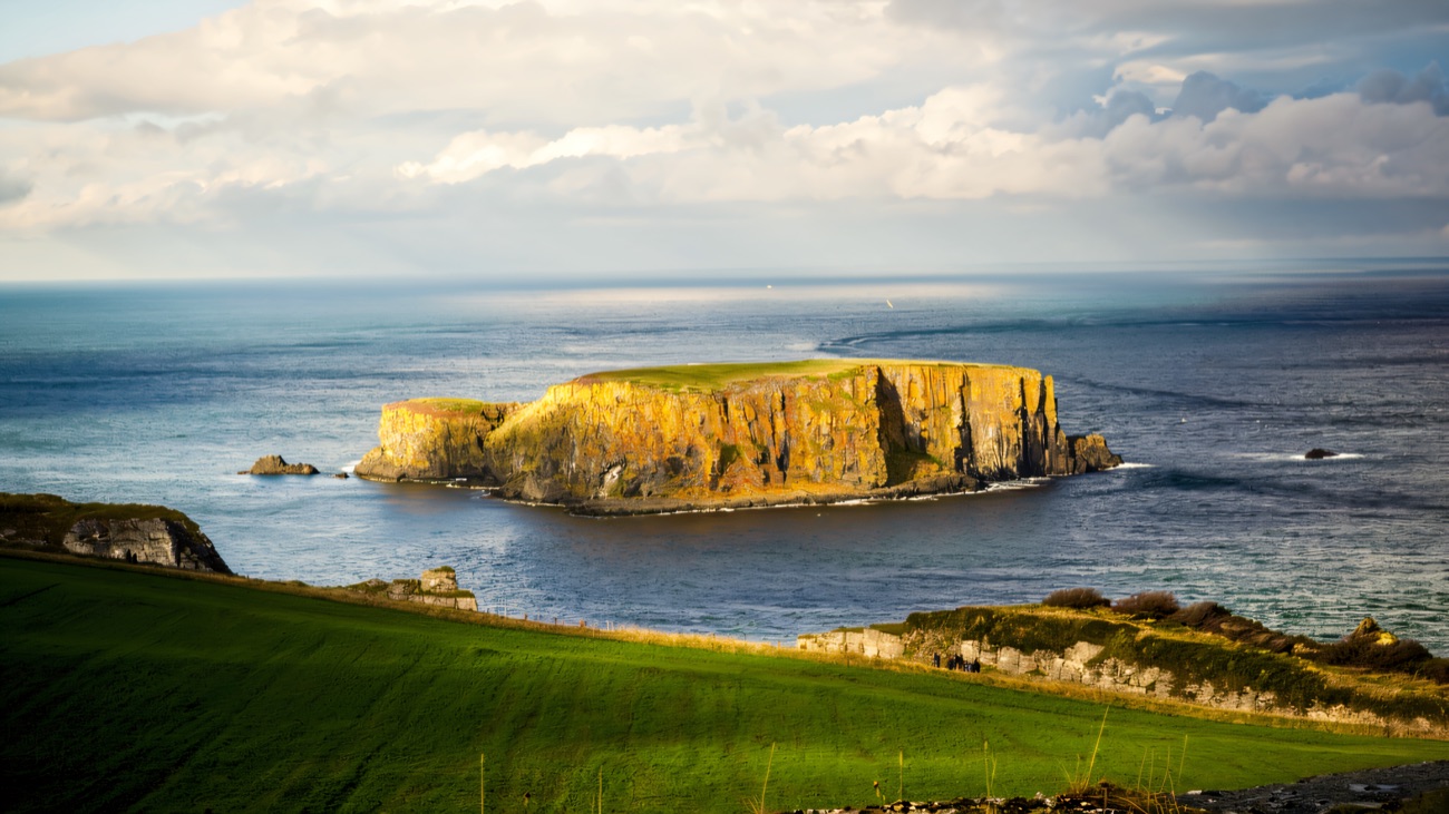 Sheep Island rising golden from the sea seen from the Carrick-a-Rede coast