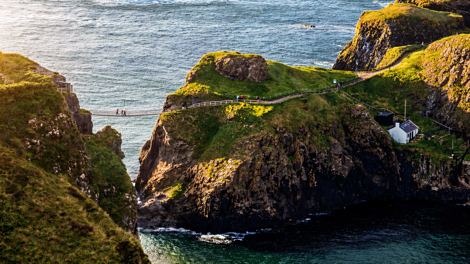 The Carrick-a-Rede rope bridge, island and cottage seen from the clifftop above turquoise sea