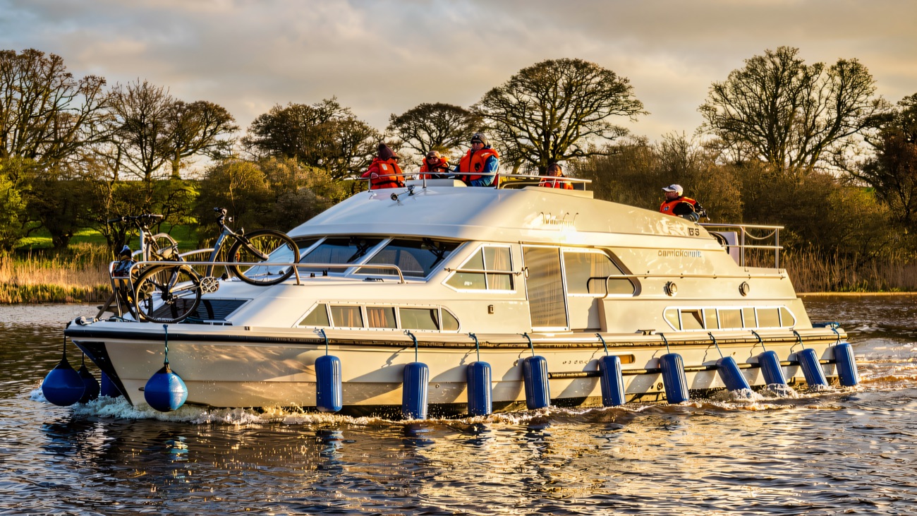 A Carrickcraft cruiser motors along the tree-lined lough, crew up top and bikes stowed on deck