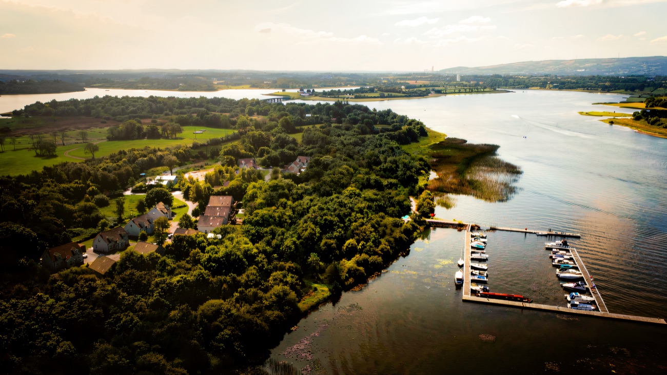 A bird's-eye view of a lough-side marina with cruisers lined along the pontoons