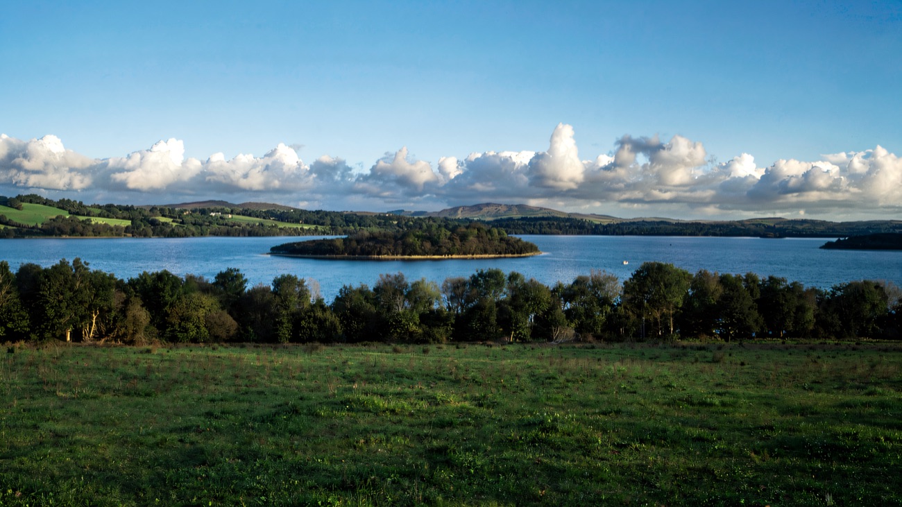 Lower Lough Erne on a bright day, a wooded island out on the water with green hills beyond