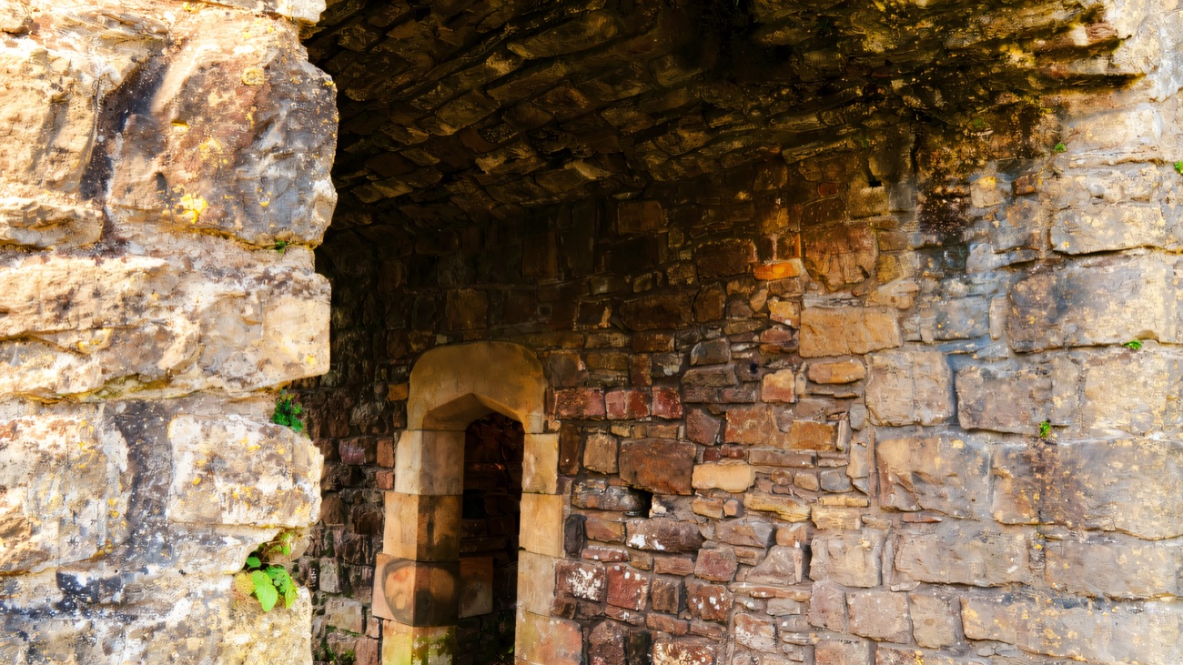 The stone gatehouse arch at Castle Caulfield, a moss-covered vaulted passage leading through to an inner doorway