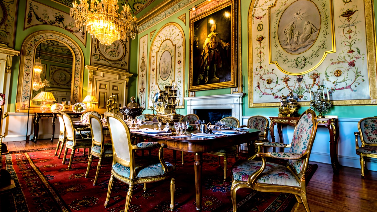 An opulent gilded state dining room inside Castle Coole, with chandelier and green painted walls