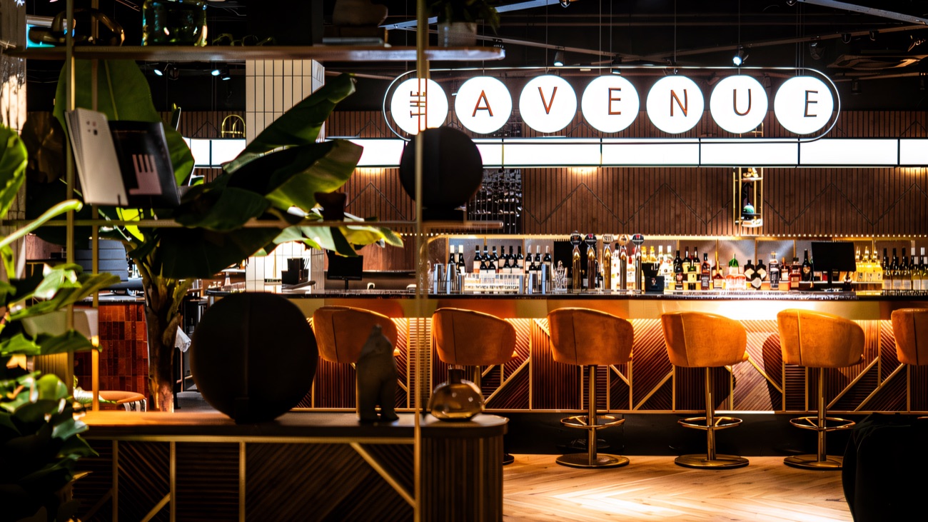 The bar at The Avenue Cinema, Café and Bar on the first floor of CastleCourt, with velvet stools and the illuminated Avenue sign