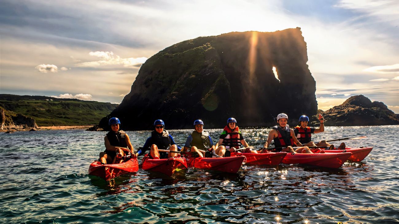 The whole group lined up in front of a dramatic sea arch off Ballintoy