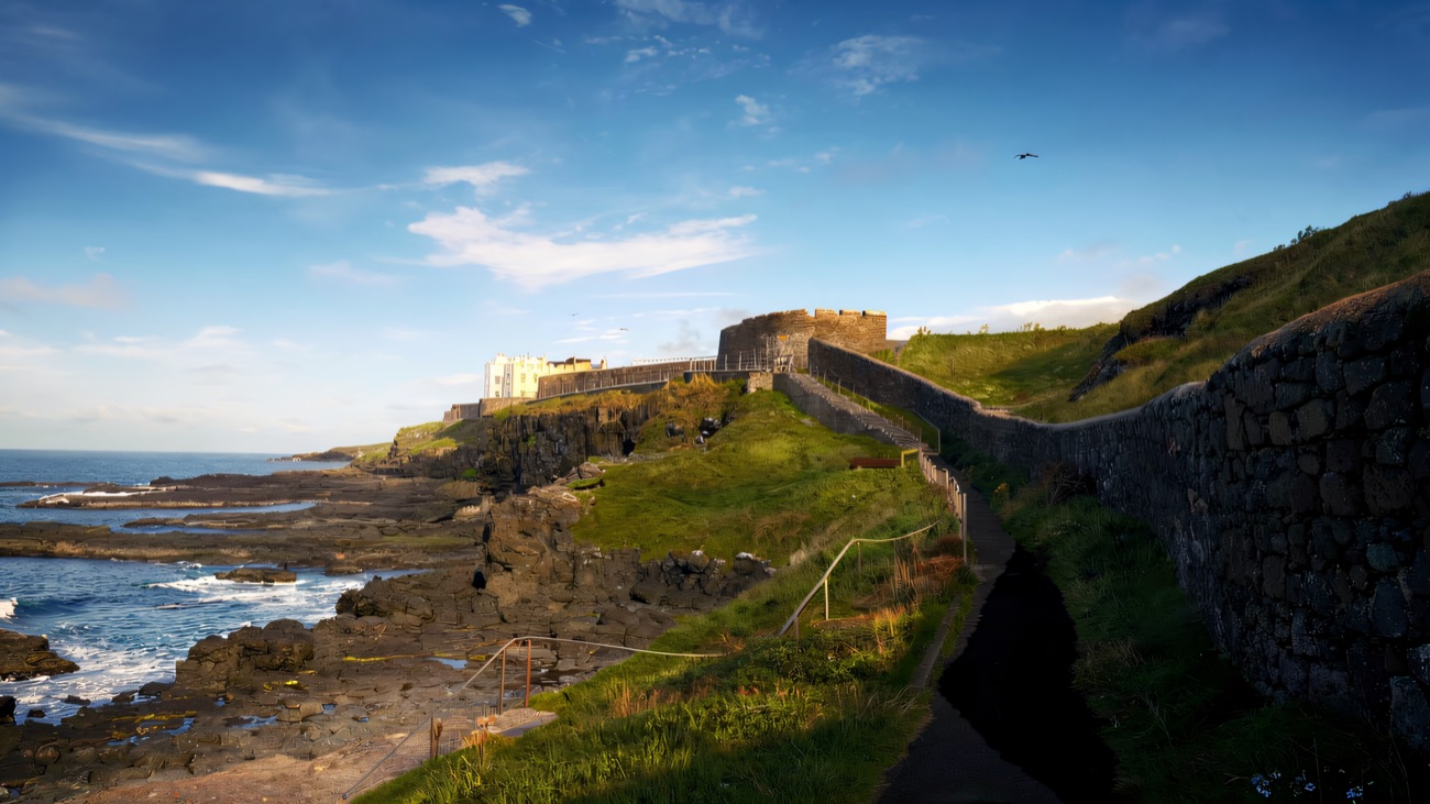 A walled coastal path threads along the rocky shore above the Atlantic