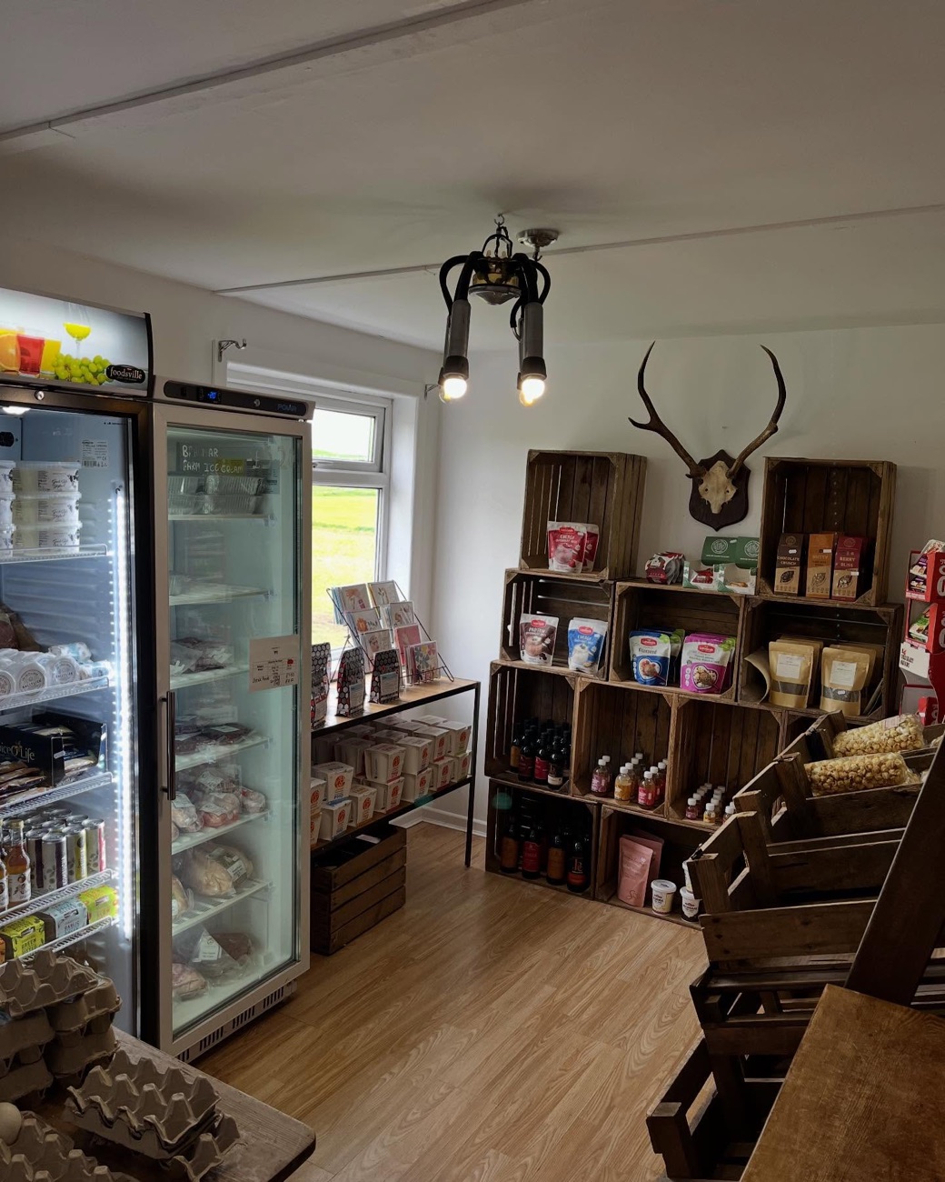 Inside the farm shop — chilled cabinets of dairy and meat, wooden crates of local produce and boxes of fresh eggs