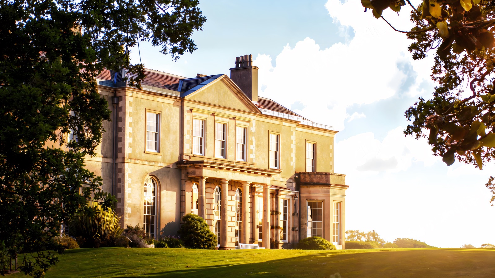Clandeboye House, a Georgian mansion, framed by oak trees above a broad green lawn