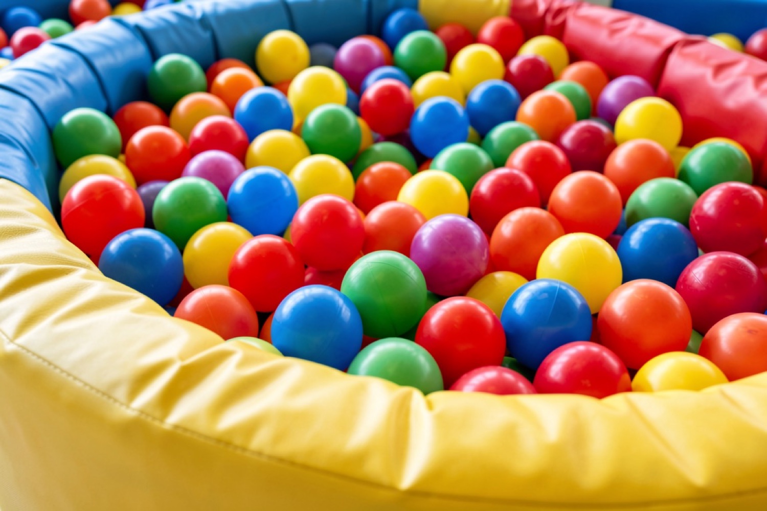 A colourful soft-play ball pool with a padded surround (illustrative of an indoor soft-play centre)