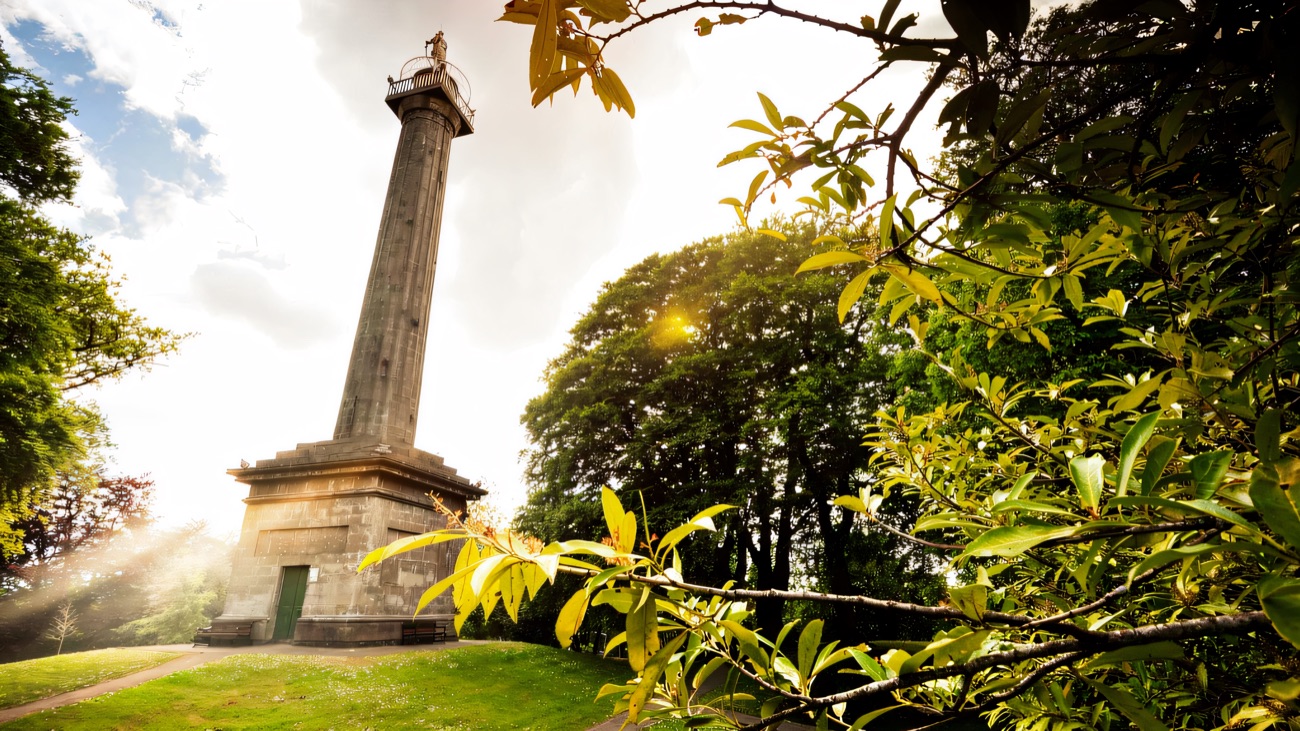 The monument framed by summer foliage on its green rise above Enniskillen