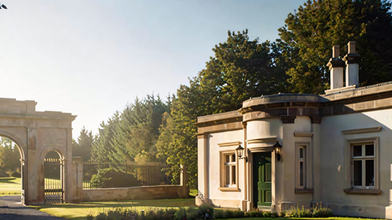 The estate's triumphal-arch entrance and a rendered gate lodge cottage in morning sun