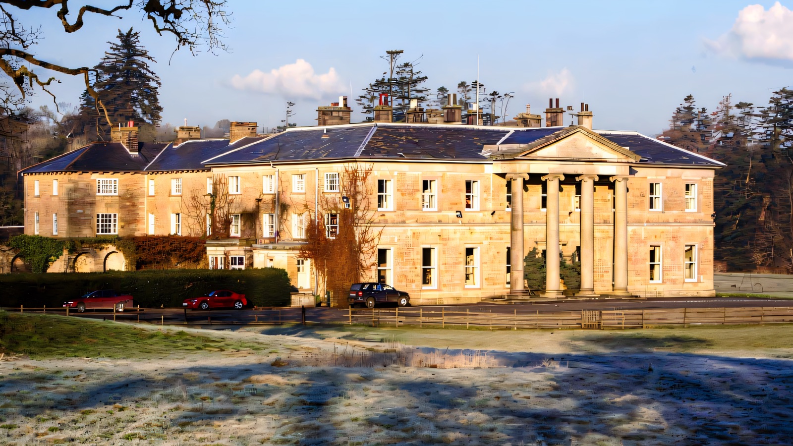 The Georgian sandstone front of Colebrooke Park with its tall columned portico, seen across frosty parkland