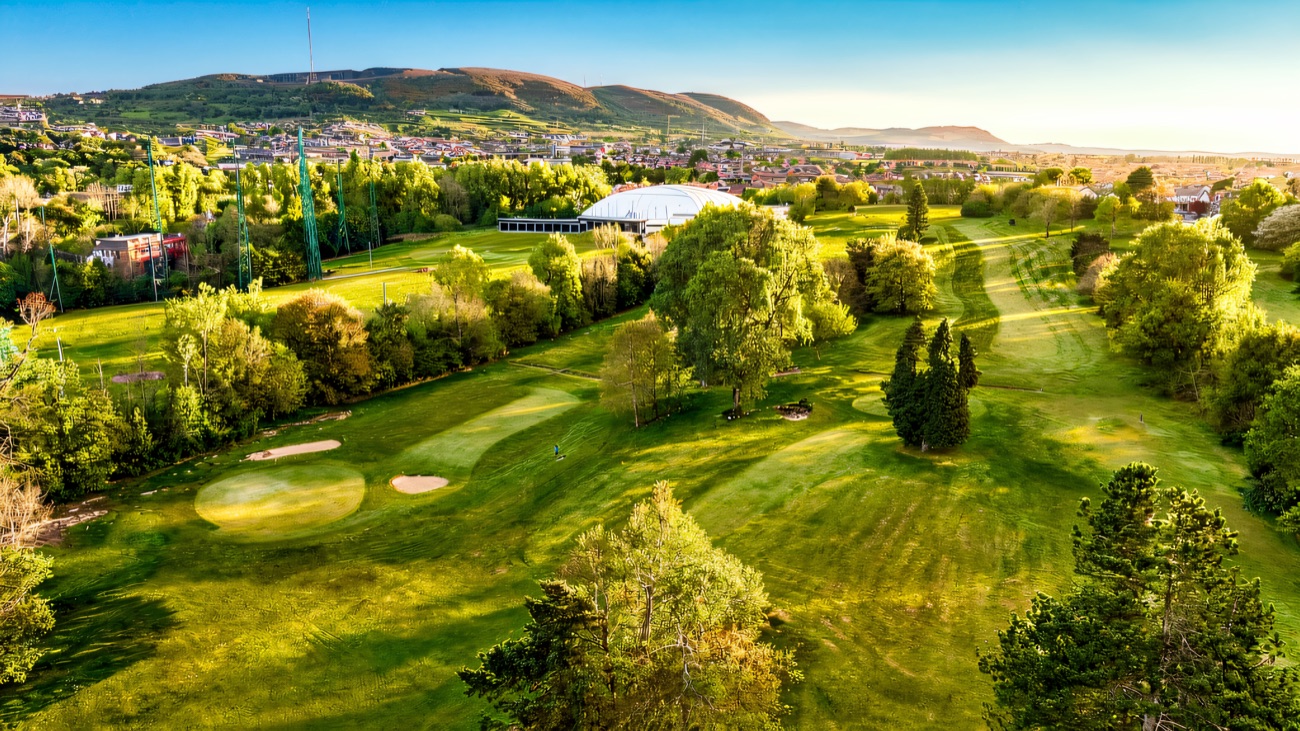 Aerial view over the course and the white activity dome with the hills behind
