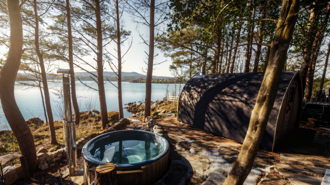 Wood-fired hot tub and the glass-fronted sauna cabin sitting at the water's edge