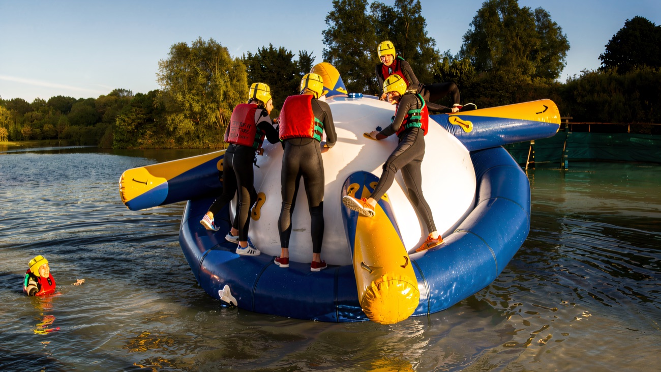 A whole crew clinging to the spinning inflatable on a sunlit lake