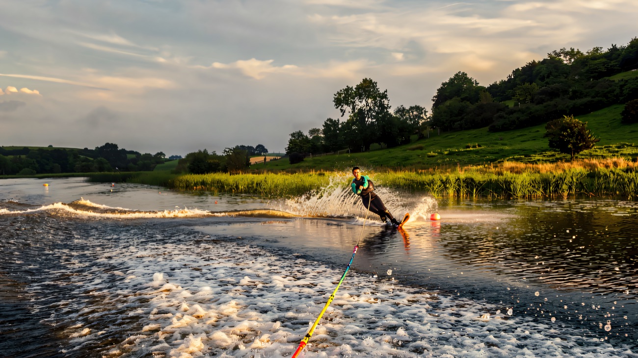 Water-skier carving a wall of spray across a glassy drumlin lake