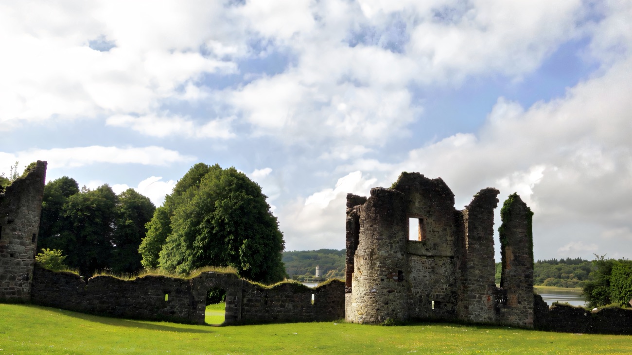 The Old Castle ruins at Crom rising from the grass above Upper Lough Erne, a broken stone tower and walls under a bright sky