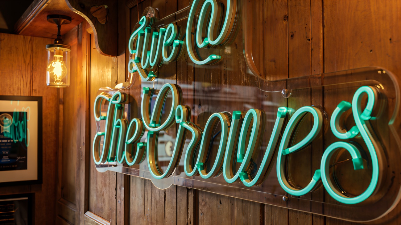 Neon Live @ The Crowes sign glowing above the bar seating