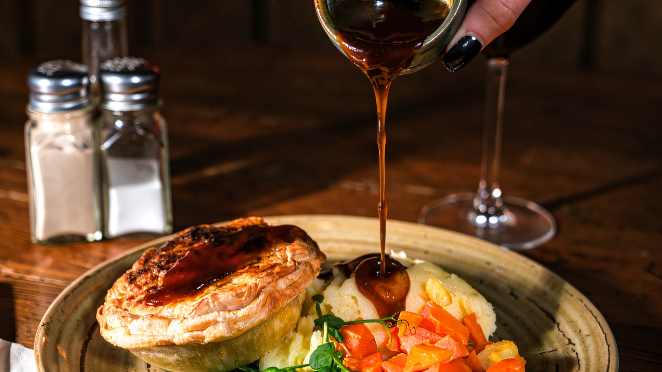 A pie dinner with gravy served at a table in the pub