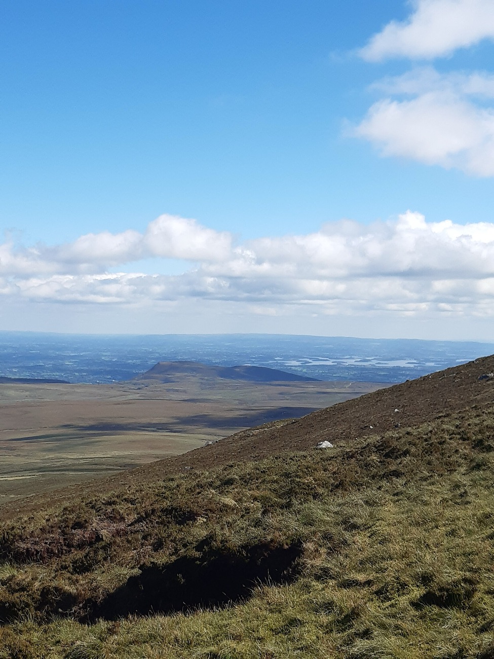 The wide view from high on Cuilcagh, looking out over the Fermanagh lowlands under a bright sky.