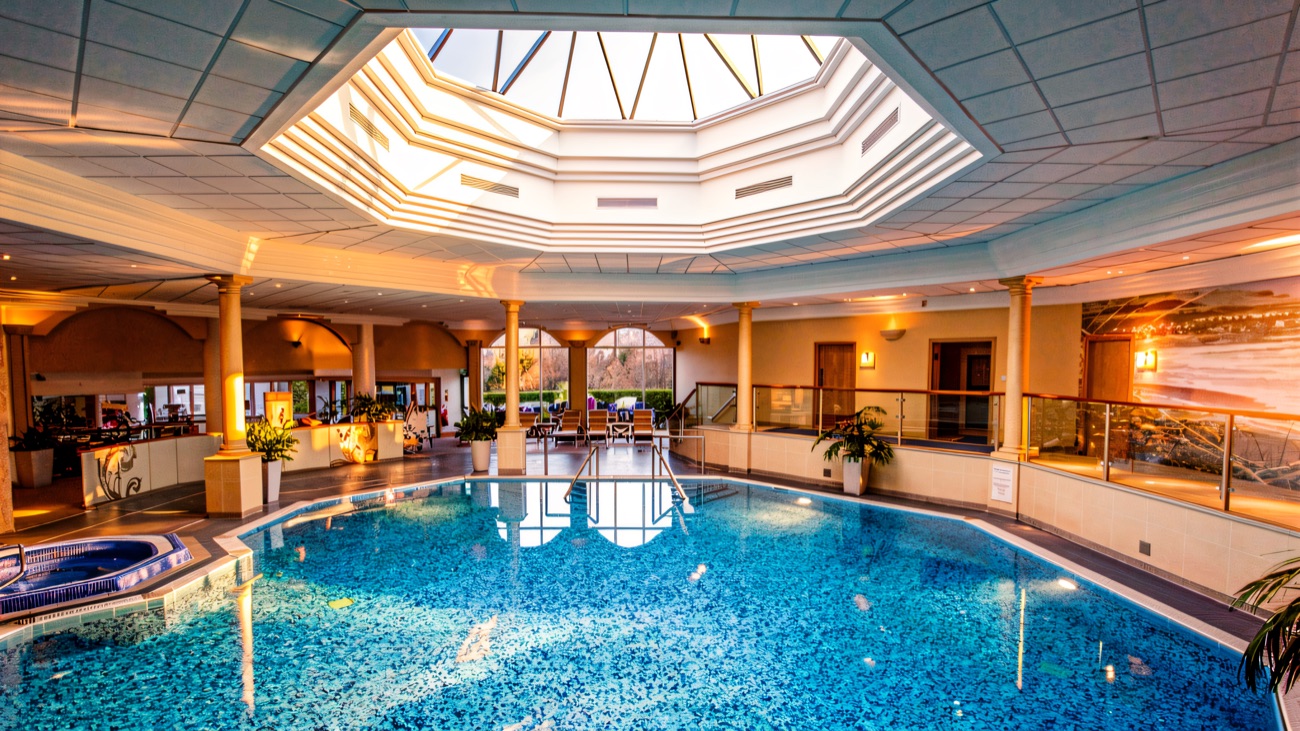 The pool under its octagonal skylight, with a corner jacuzzi and arched garden windows.