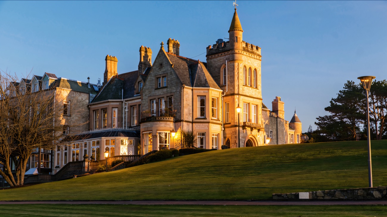 The Victorian estate house in warm sandstone, set above sloping green lawns.