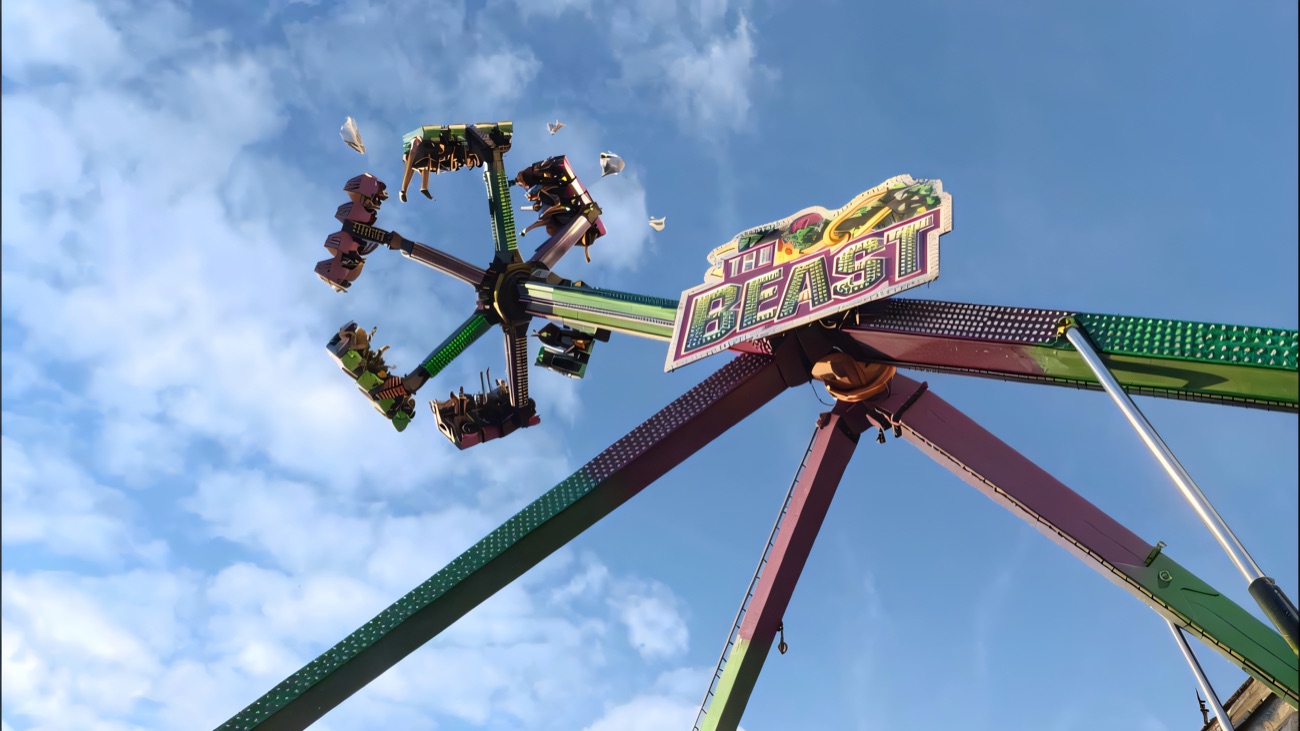 The Beast pendulum swing ride spinning riders high against a bright blue sky