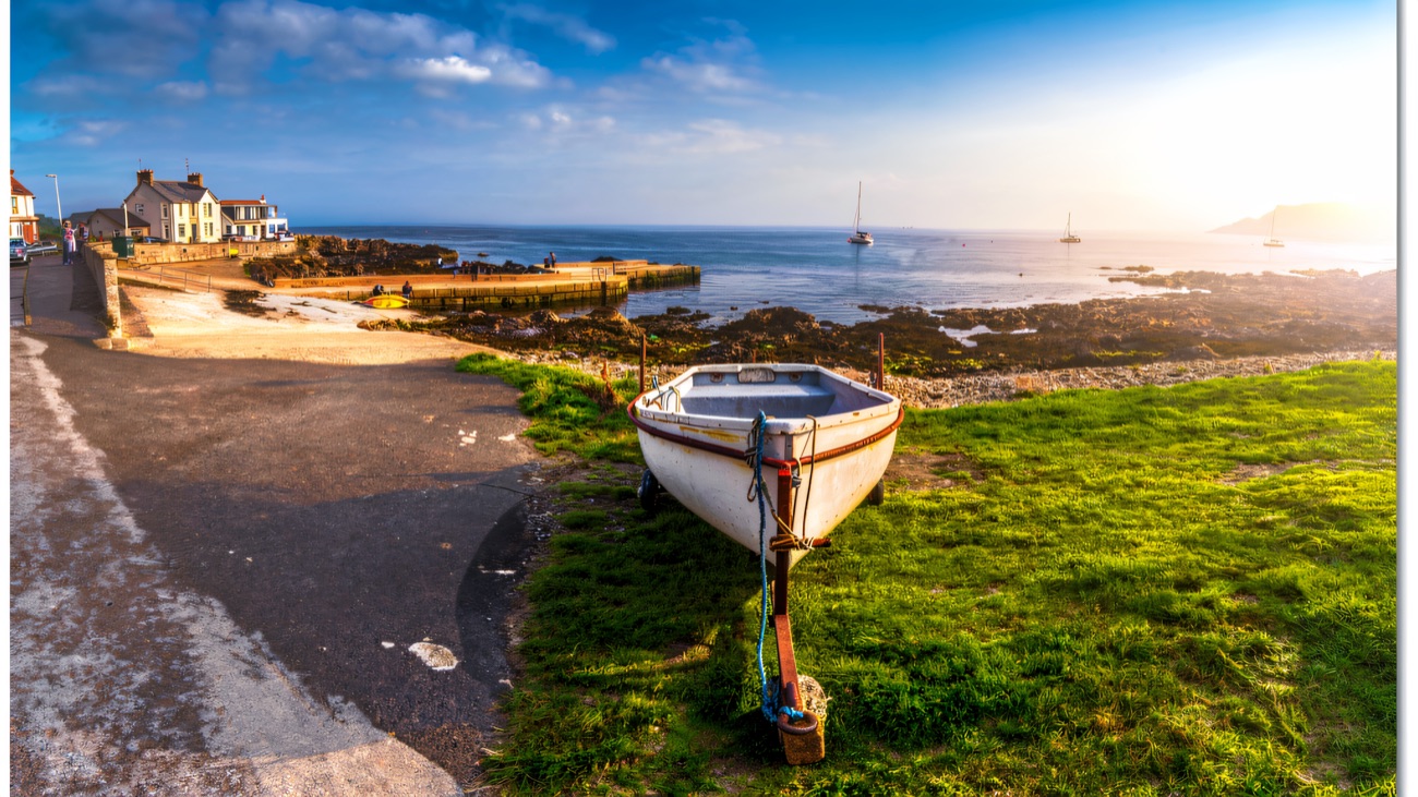 A dinghy pulled up on the shore, the Antrim coast glittering beyond