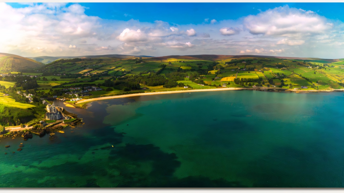 Aerial view of Cushendun bay, turquoise water and the green Glens of Antrim