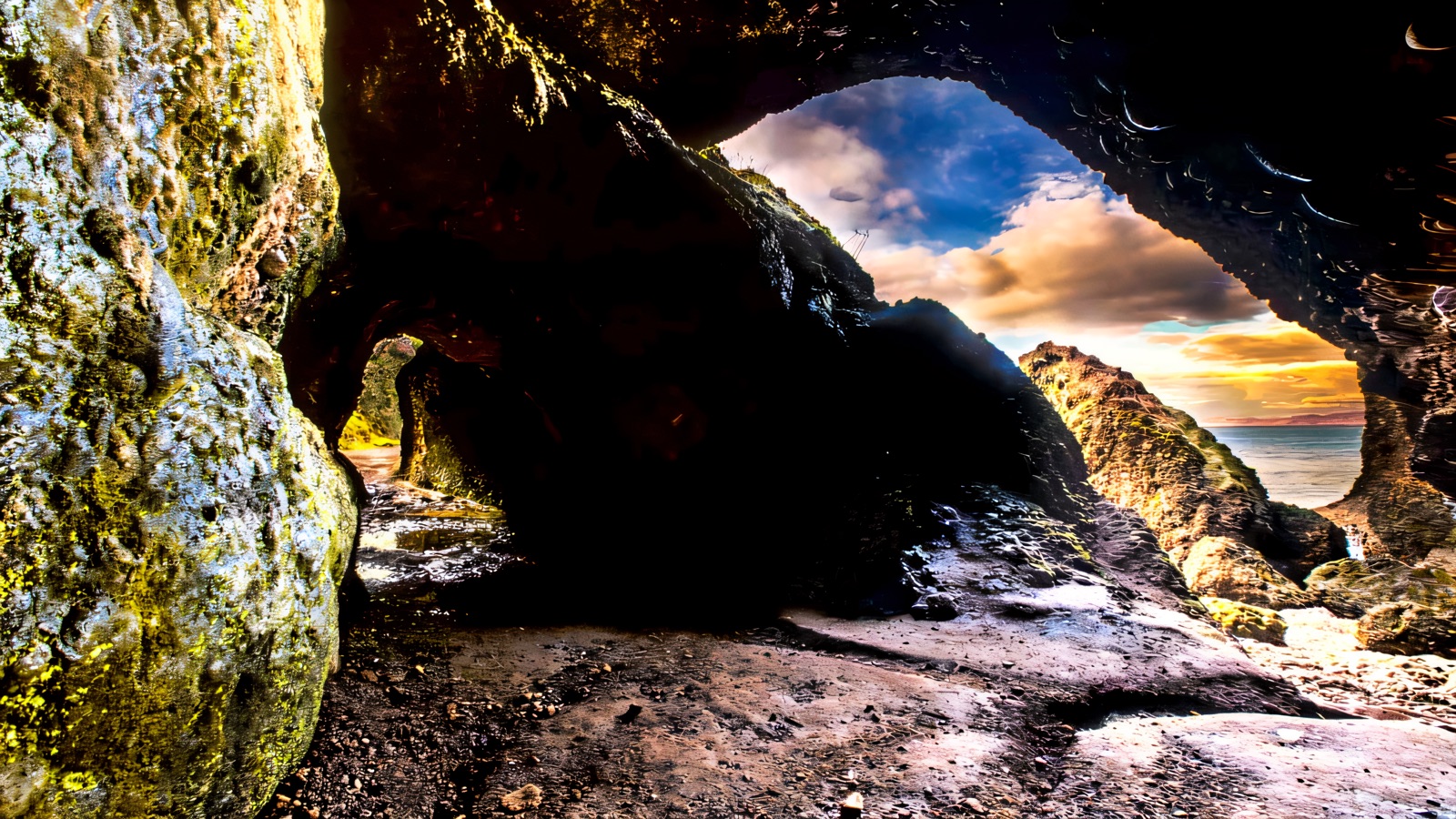 Looking out from inside a Cushendun sea cave through a rock arch to the sea and a glowing sky