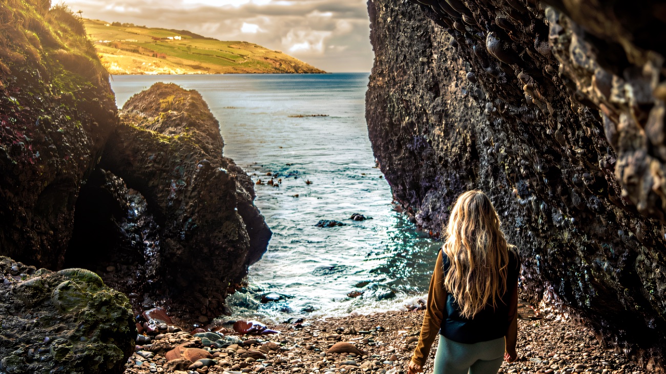 A walker at the mouth of a sea cave on the Cushendun shore