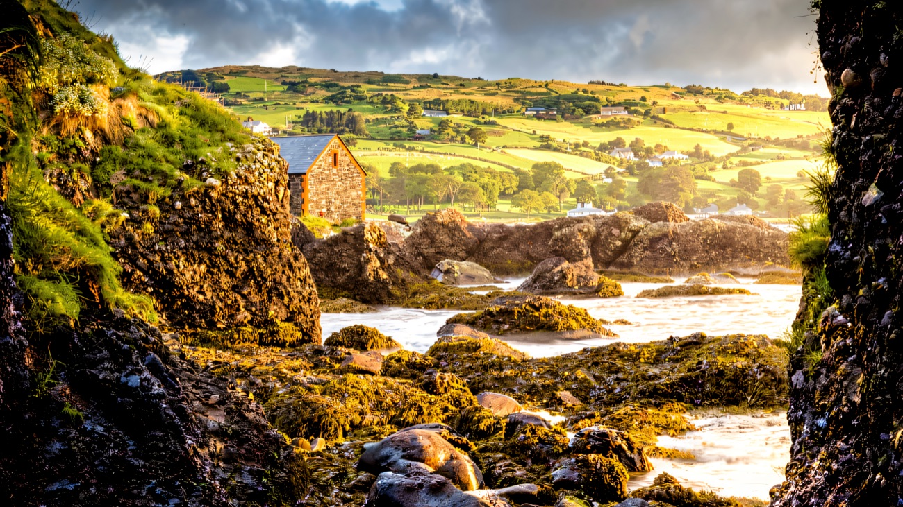 A stone cottage across the rocky Antrim coast under moody skies