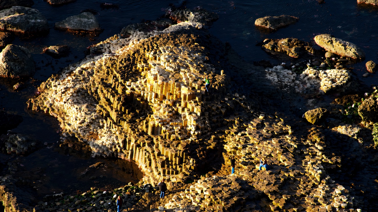 A bird's-eye view of the hexagonal basalt columns at the Giant's Causeway, with visitors exploring the stones