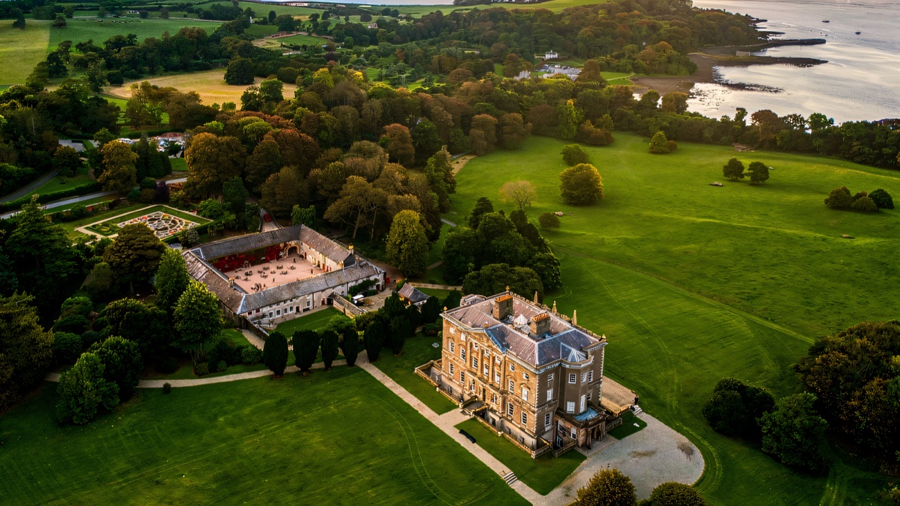 Aerial view of Castle Ward house, its farmyard and green parkland running down to Strangford Lough