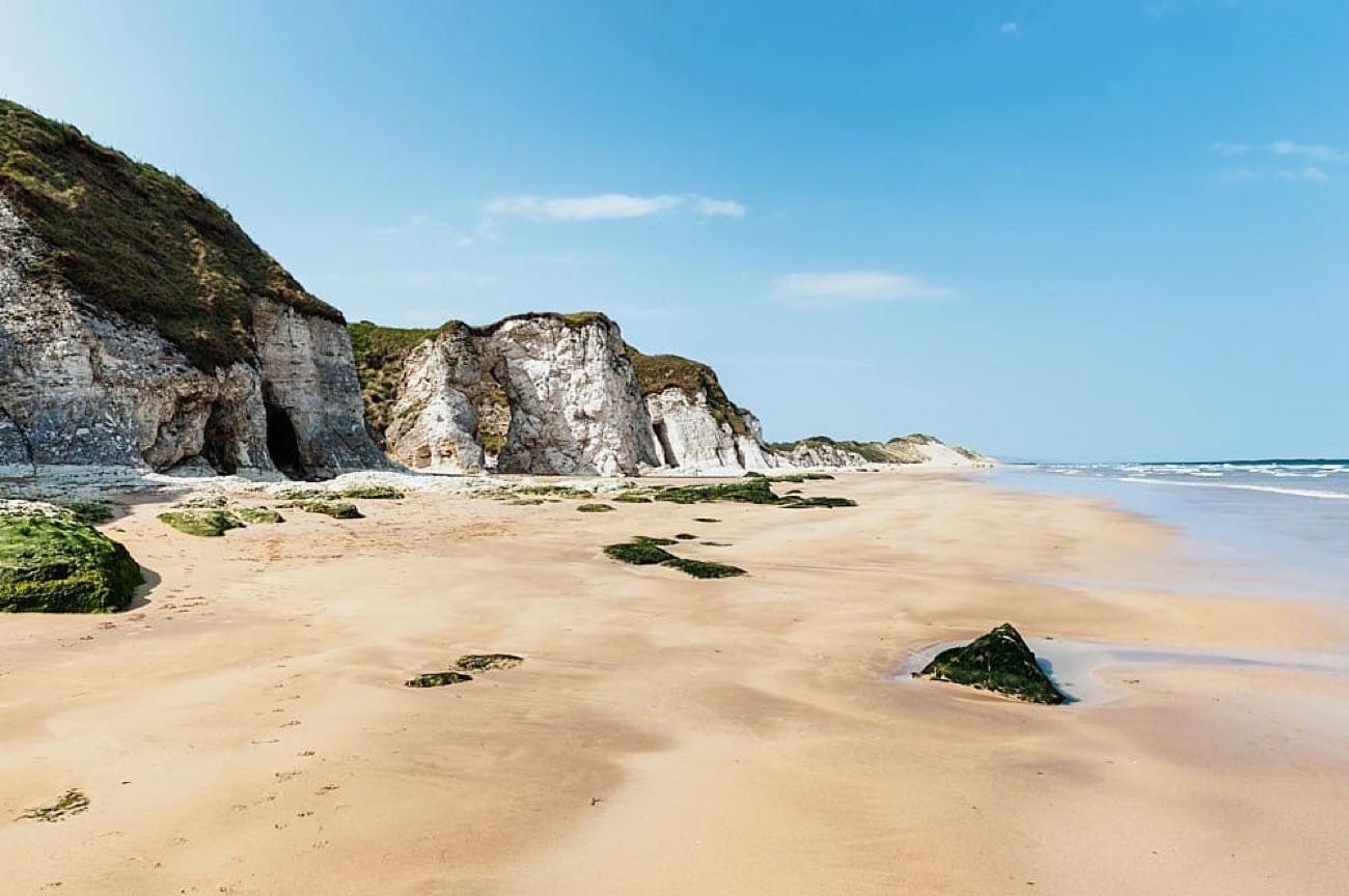 Golden sand and white limestone cliffs under a clear blue sky at Whiterocks Beach
