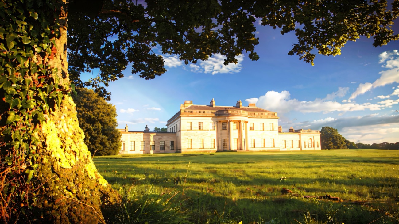 The pale Portland stone front of Castle Coole glowing in evening light across its parkland