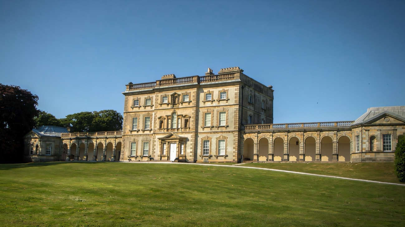 The Georgian front of Florence Court with its arched colonnades under a clear blue sky