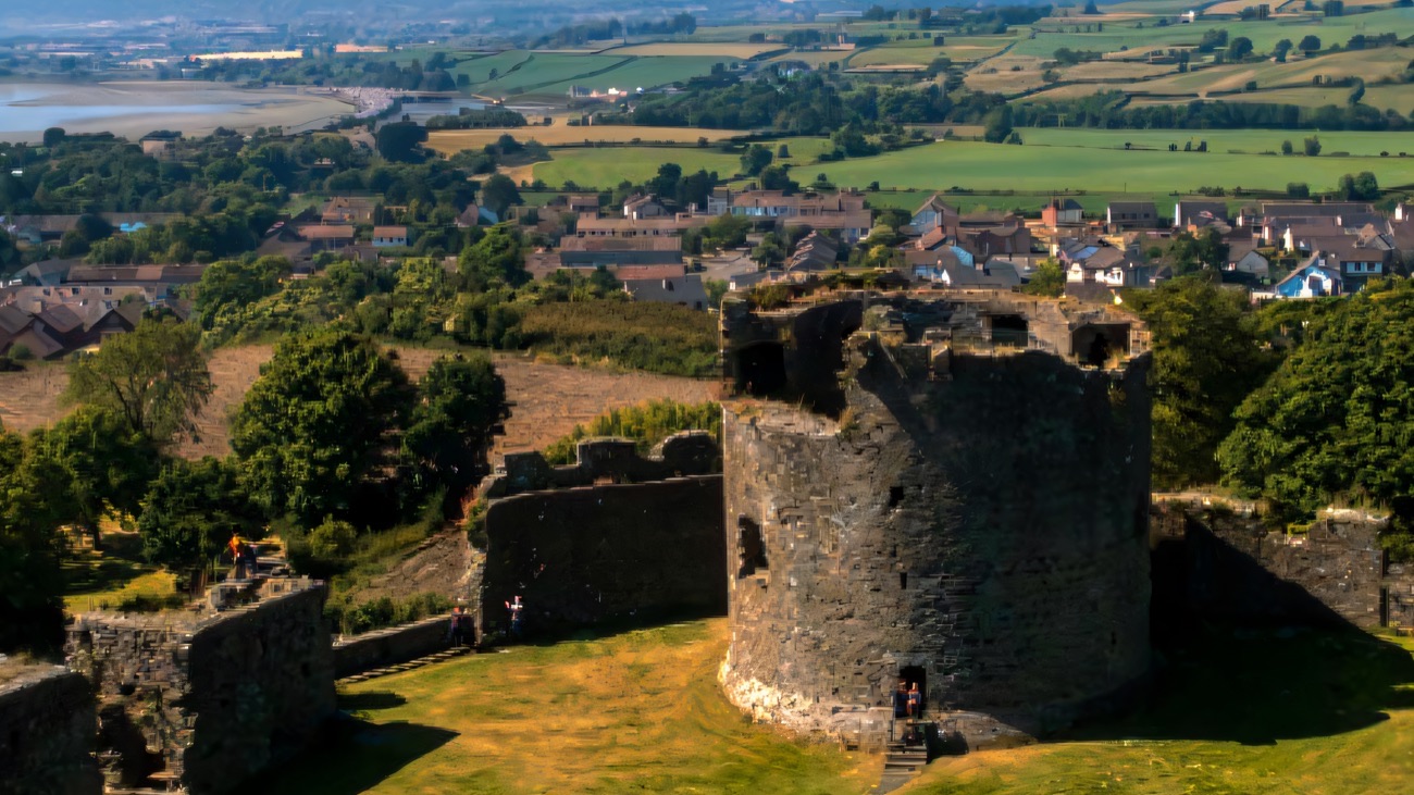 The round keep of Dundrum Castle seen from above, with the village, green fields and Dundrum Bay stretching behind