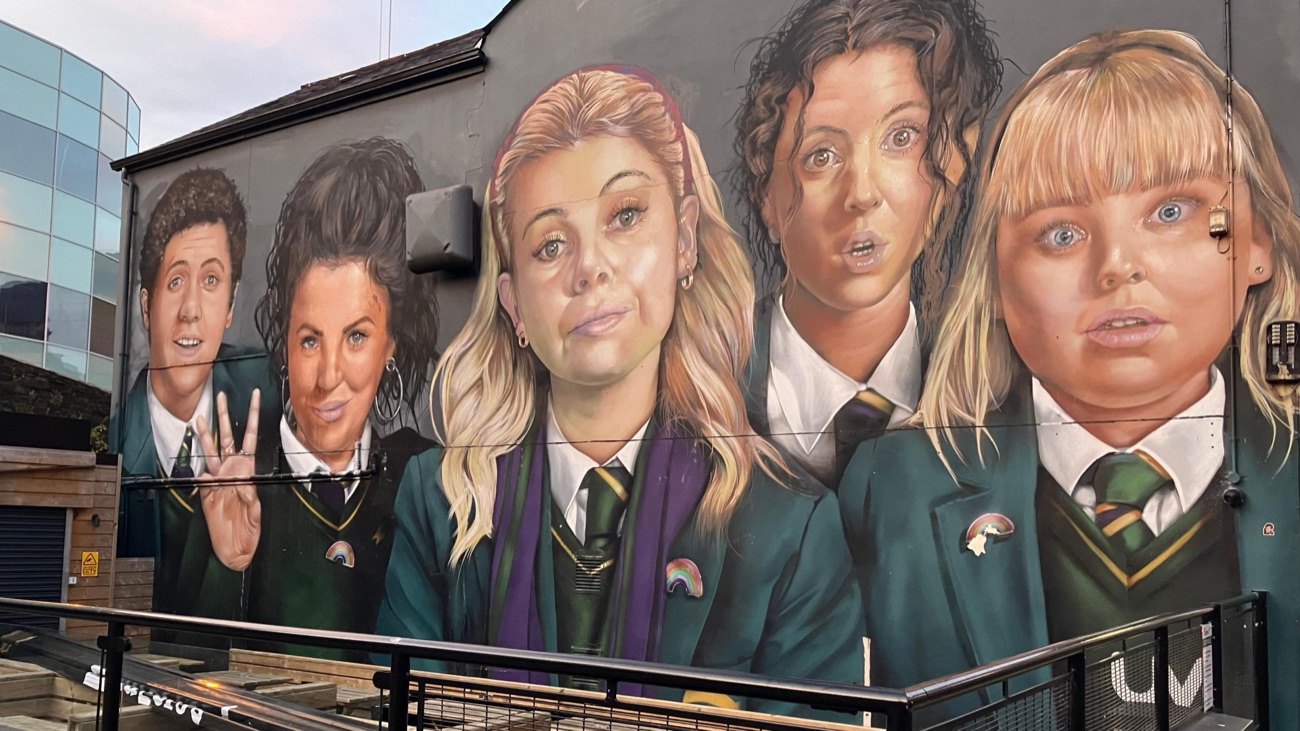 Close-up of the mural — the four Derry Girls and James painted large in their green school uniforms