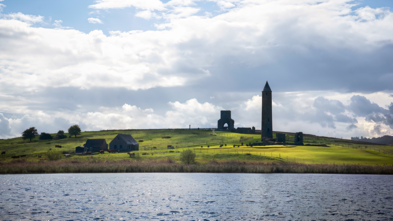 The monastic ruins seen across the water, cattle grazing the island slopes