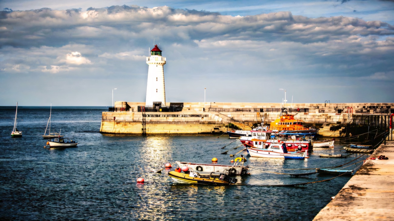Donaghadee's white lighthouse guards the harbour mouth above the moored fishing boats.