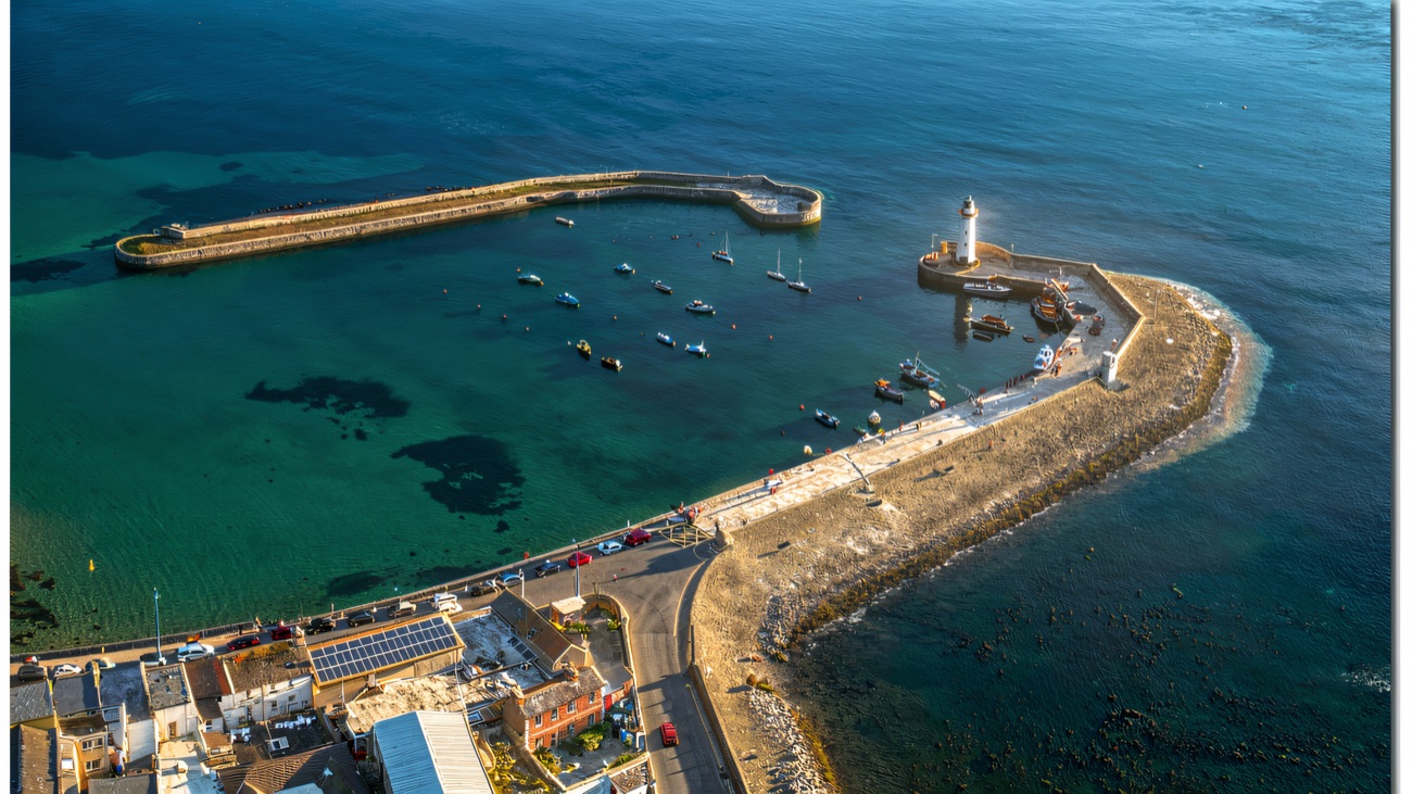 Aerial view of the long curving pier wrapping around Donaghadee harbour, with the lighthouse at its tip