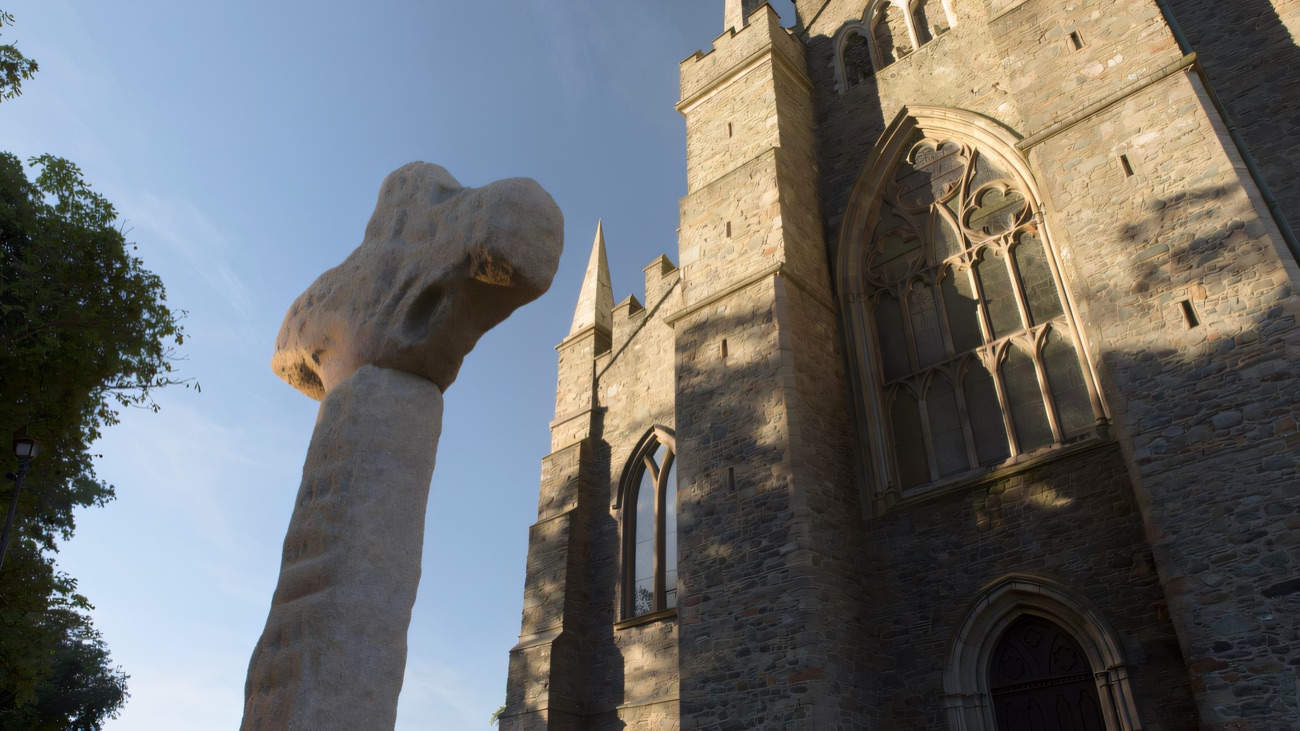 The ancient high cross against the Gothic west front in golden evening light