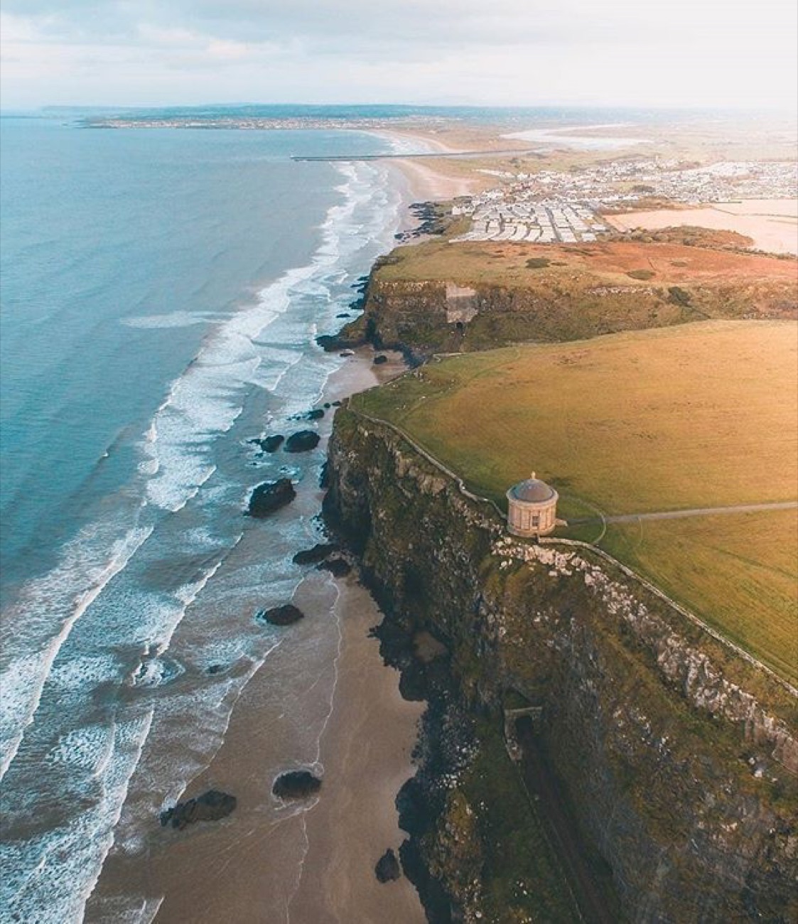 Aerial view of Downhill Beach with Mussenden Temple on the clifftop and the strand curving into the distance toward Castlerock