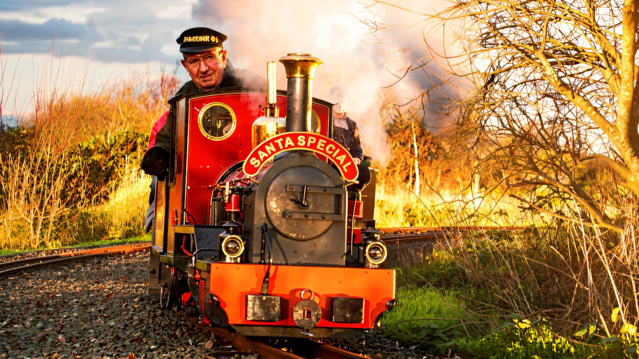 A miniature steam locomotive under steam on the line.
