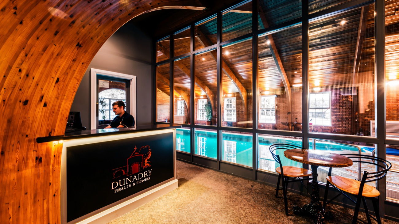 The Dunadry Health & Fitness reception under a timber arched roof, with the indoor pool beyond the glass.