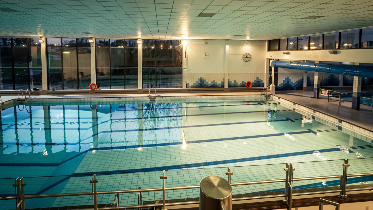 The bright indoor swimming pool with tiled wave detail and a wall of windows